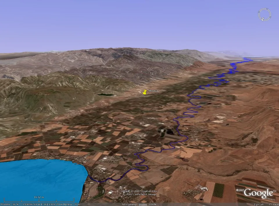 Aerial / 3D oblique view of the area around Tell esh Shuna in Google Earth, showing the alluvial fan of the Wadi Arab south of the Yarmouk River, the Jordan Valley floor to the west, and the eastern terraces rising sharply behind the site.